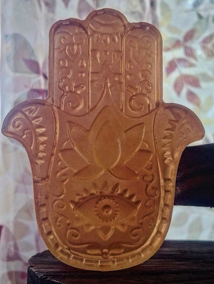Decorative Hamsa hand with intricate designs on a wooden stand against a blurred background